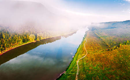 Flight through majestic foggy river and lush green forest at sunrise time. Landscape photography....