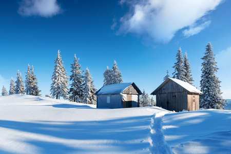 Fantastic winter landscape with wooden house in snowy mountains. Christmas holiday concept