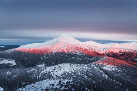 Fantastic orange winter landscape in snowy mountains glowing by sunlight. Dramatic wintry scene with...