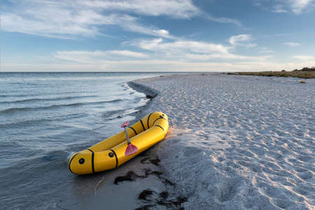 Yellow packraft rubber boat with red padle on a sea coast. Packrafting. Active lifestile conceptの写真素材
