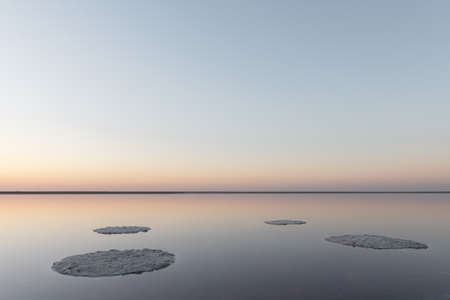 Tranquil minimalist landscape with smooth surface of the pink salt lake with calm water with horizon with clear sky in sunrise time. Simple beautiful natural calm backgroundの写真素材