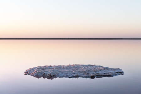 Tranquil minimalist landscape with smooth surface of the pink salt lake with calm water with horizon...
