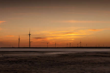 Tranquil landscape with rows offshore wind turbines on dry seabed on sunset time. Industrial...
