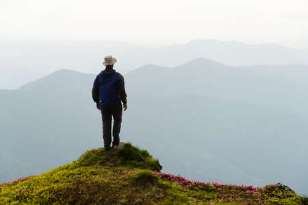 A tourist stay on the edge of a cliff covered with a pink carpet of rhododendronの写真素材