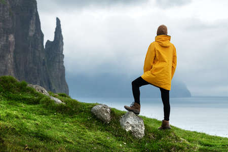 Tourist with backpack in yellow jacket looks at Witches Finger cliffsの写真素材