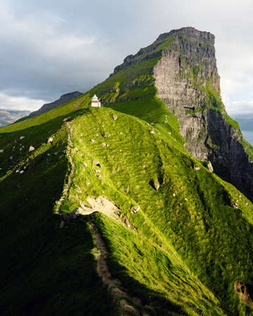 Kallur lighthouse on green hills of Kalsoy islandの写真素材
