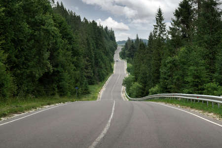 Curvy mountain road serpentine in green summer forestの写真素材