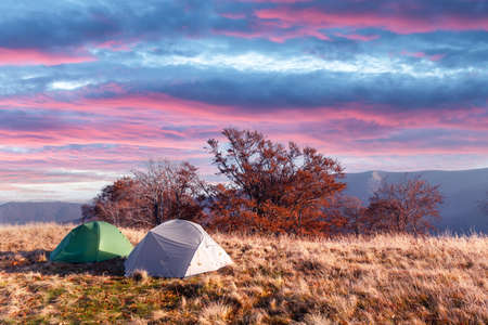 Two tents on amazing meadow in autumn mountains
