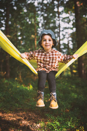 Small kid in yellow hammock in autumn forestの写真素材