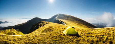 Lonely yellow tent against the backdrop of an incredible mountainsの写真素材