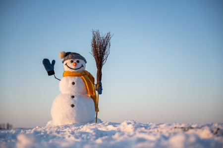Snowman with broom on snowy fieldの写真素材