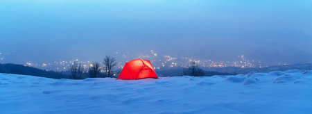 Winter panorama with red tent lighted from the insideの写真素材