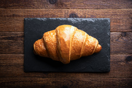 Freshly baked croissant on a black slate boardの写真素材