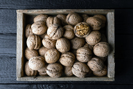 Walnut nuts in a wooden box on old wooden tableの写真素材