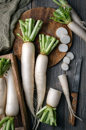 White daikon radish roots with knife and round boardの写真素材