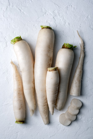 Whole and chopped white daikon radish roots on white backgroundの写真素材