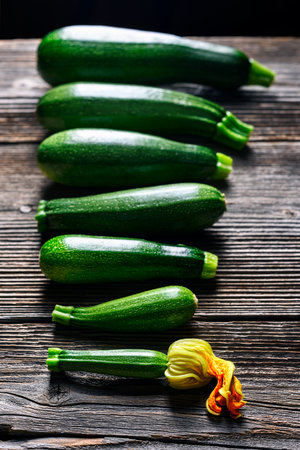 Zucchini laid out on a rustic wooden table in a rowの写真素材