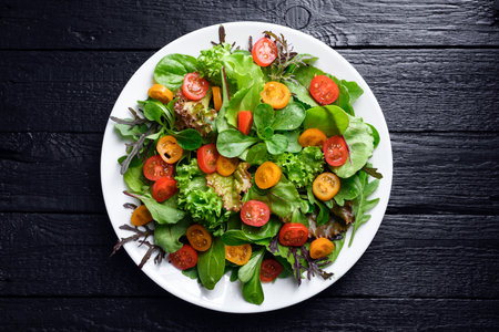 Mix of fresh organic juicy salad greens on black tableの写真素材