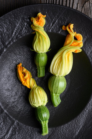 Young fresh zucchini with flowers in black plateの写真素材