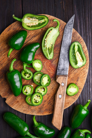 Sliced green jalapeno hot peppers on round wooden cutting boardの写真素材