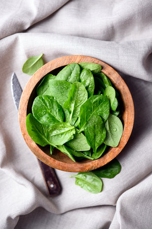 Baby spinach leaves in a wooden bowlの写真素材