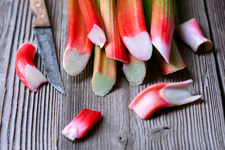 Ripe pink rhubarb stalks with knife on a wooden tableの写真素材