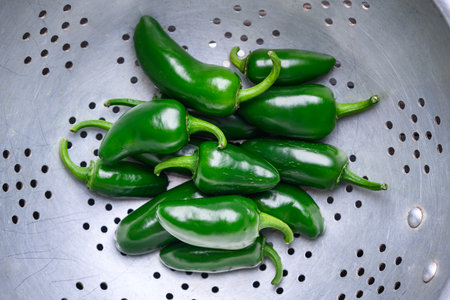 Green mexican jalapeno hot peppers in a metal colander