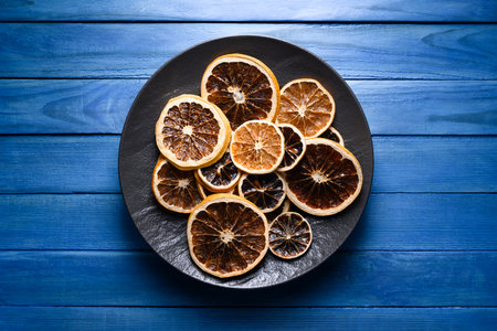 Dried citrus slices in black plate on rustic wooden blue tableの写真素材