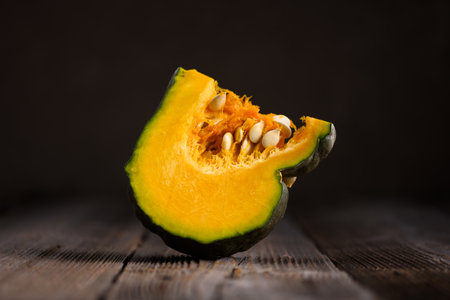 Piece of green pumpkin with orange flesh and seeds