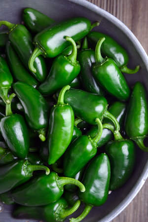 Top view on metal colander filled with green jalapeno peppers