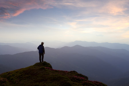 Scenic mountain landscape with a traveler gazing at a stunning sunsetの写真素材