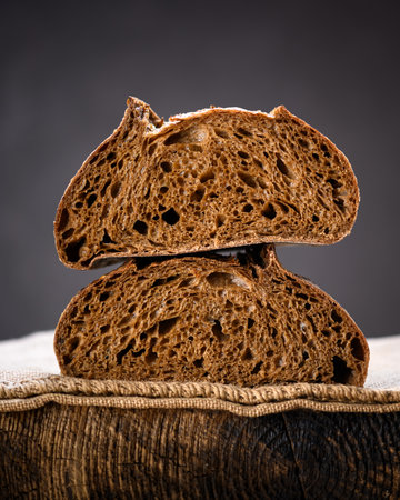 Two half of rye sourdough bread in section on a rustic wooden board