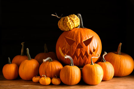 Scary jack-o-lantern in center of tiny orange pumpkinsの写真素材