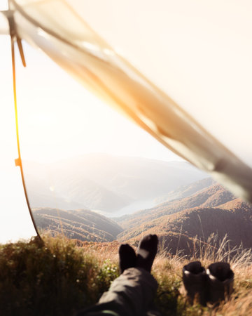 Autumn hiker rests in tent with open view of mountain lakeの写真素材