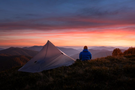 Hiker near his tent against the backdrop of an incredible sunset skyの写真素材
