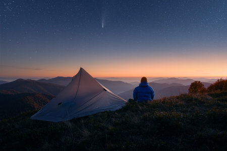 Traveler near his tent against the backdrop of an incredible starry sky