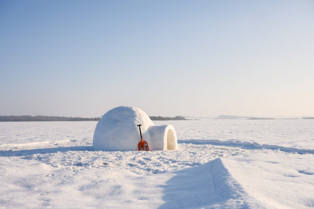 Igloo with snow shovel on the winter field