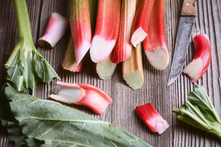 Rhubarb stems and sliced pieces arranged on wooden backgroundの写真素材