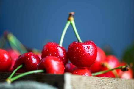 Pile of cherries with green leaf on rustic surface