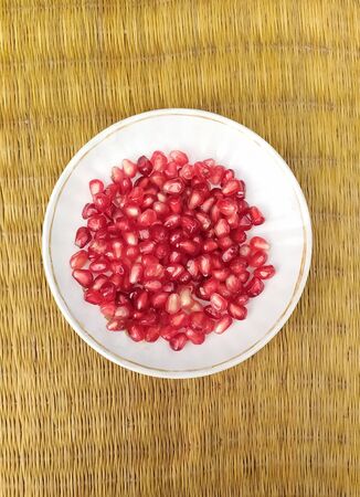 Red juicy pomegranate seeds on plate.の写真素材