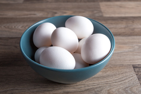 Large heap of eggs in a bowl placed on a table.