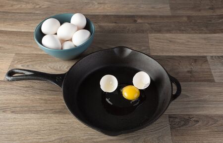 Raw eggs in frying pan with yoke showing.