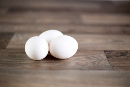 Three eggs placed on wooden table.の写真素材