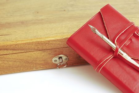 An old wood box with a calligraphy pen on top and  leather red diary  on a white backgroundの写真素材