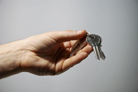Hand holding keys, blue, grey in the background
