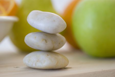 zen stones and orange, apple, pear fruits on backgroundの写真素材