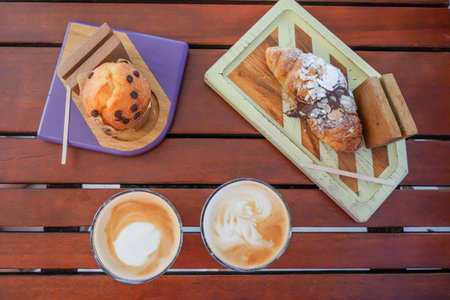 Top view of coffee, croissant and cupcake on wooden table