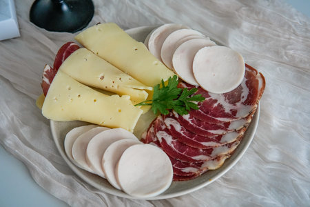 Close-up of charcuterie plate with cheese, bacon, and sausages on festive table