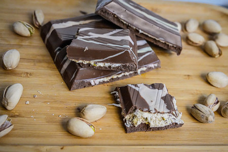 Broken Chocolate Bar with Pistachios on Table