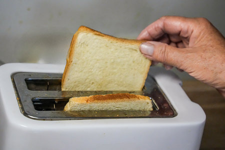Hand Taking Toasted Bread from Toaster